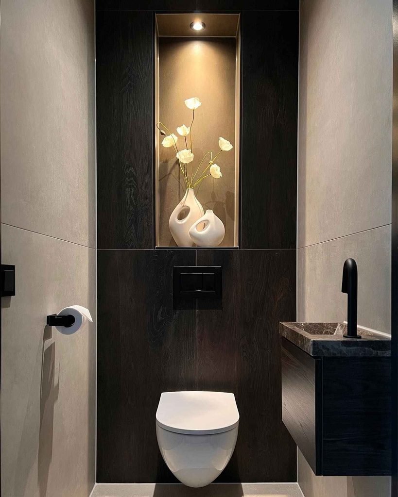 Dark colors can create a luxurious and high-end feel, even in a small toilet room. This design uses deep black wall panels, soft lighting, and modern fixtures to create a bold statement while keeping the space sophisticated.