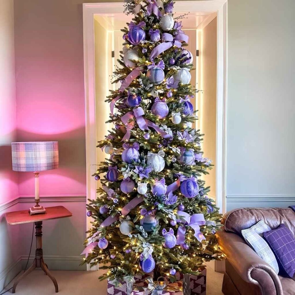 Elegant Christmas tree decorated with lavender and silver baubles, purple ribbon bows, sparkling floral accents, and warm white lights.