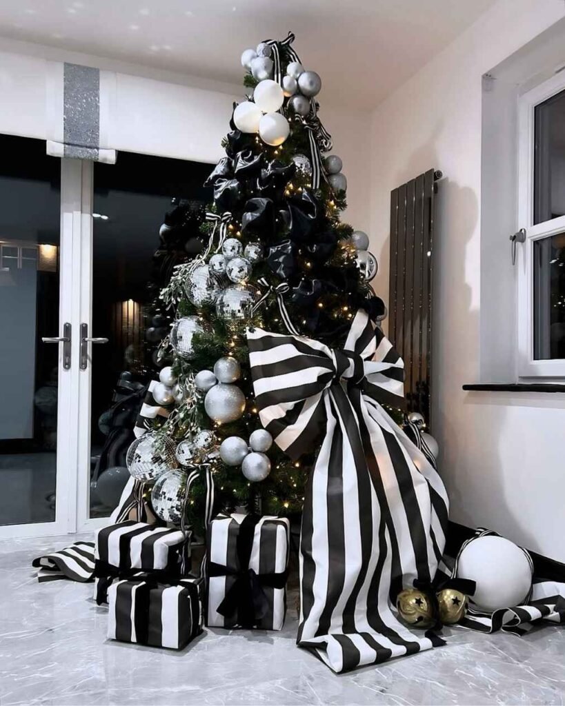 Black and white Christmas tree featuring a giant striped ribbon bow, silver disco-ball ornaments, black bows, white baubles, and matching wrapped gifts.
